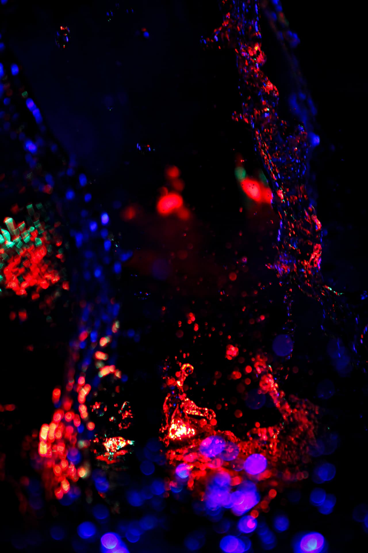 Water droplets scattering pink and violet light on black