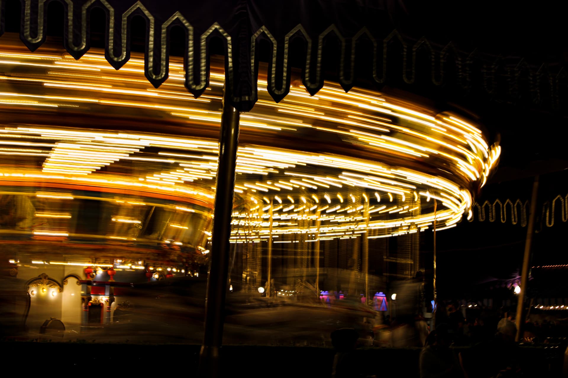 Golden carousel lights streaking as it spins at night