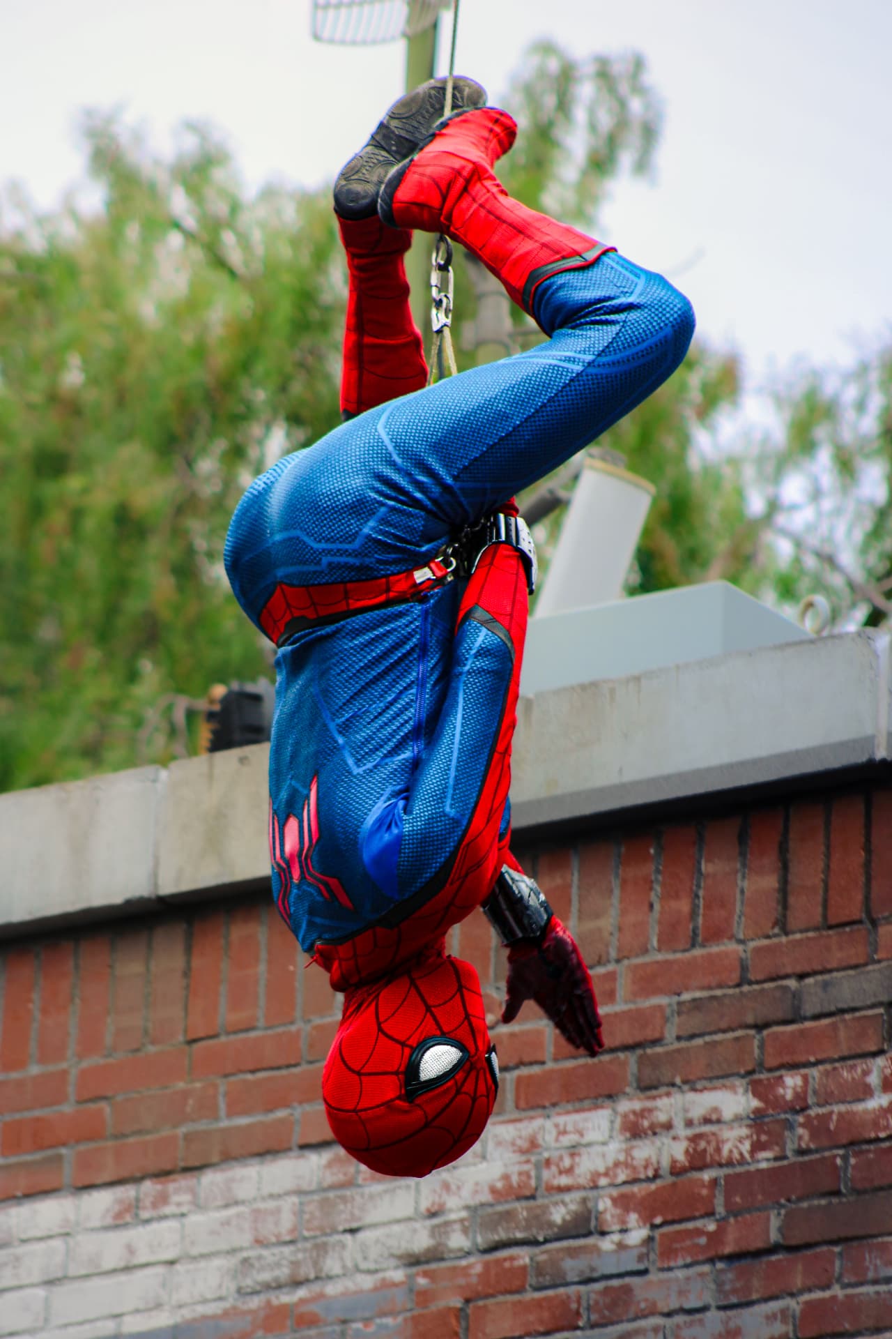 Spider-Man swinging upside down from a rooftop