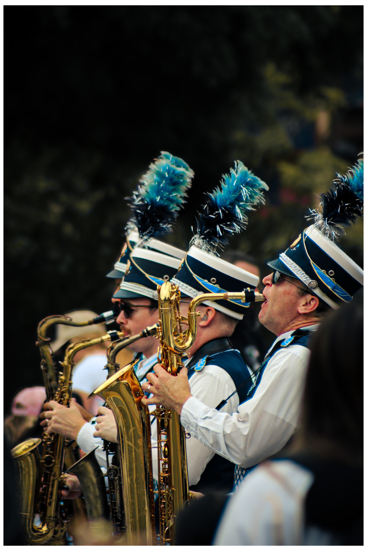 Marching band saxophonists in plumed hats playing in a parade